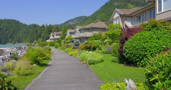 Establishing shot of two story stucco luxury house with garage door, big tree and nice landscape in Vancouver, Canada, North America. Day time on June 2021. ProRes 422 HQ.