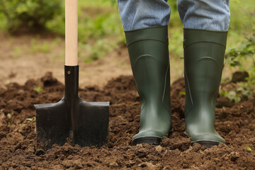 Worker in rubber boots with shovel outdoors, closeup. Gardening tool