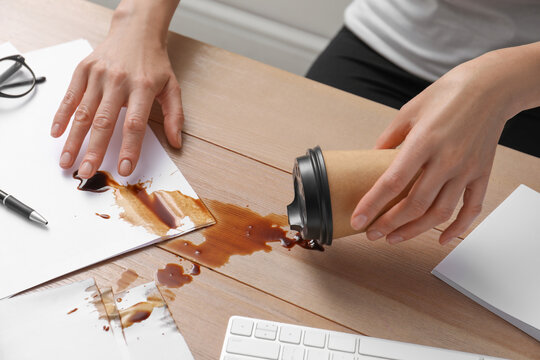 Woman Spilled Coffee On Wooden Office Desk, Closeup