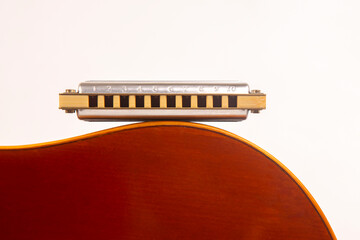 The harmonica rests on the body of a classical guitar. Classical musical wind instrument.