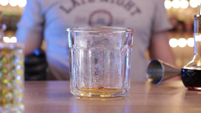 the bartender puts an ice cube in the glass with his hand
