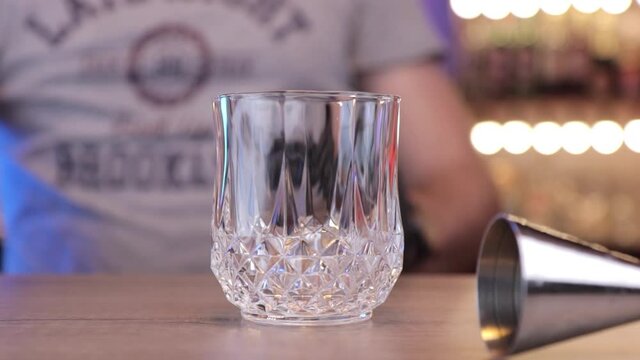 a man or bartender changes his glass from one hand to another .
