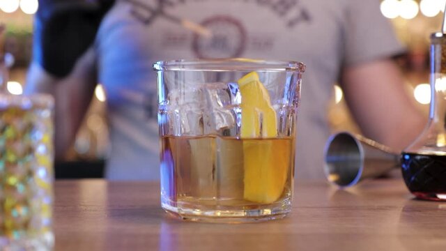the bartender decorates the cocktail with a  slice of orange