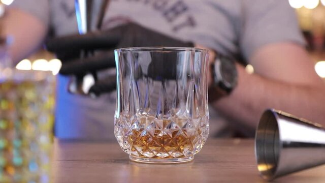 a man or bartender pours alcohol into the glass