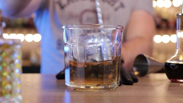 the bartender with a spoon mixes cocktail right into the glass