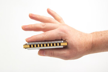 The right hand holds a harmonica on a white background. Classical musical wind instrument.