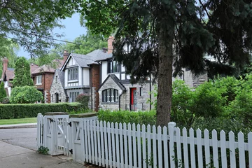 Poster Tree lined residential street with older two story Tudor style houses and white picket fence around front yard © Spiroview Inc.