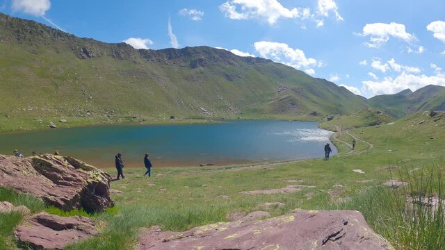 Timelapse of a mountain lake in summer with some excursionists