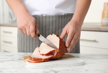 Man cutting delicious ham at white marble table indoors, closeup
