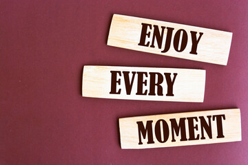 Enjoy every moment write on brown background.