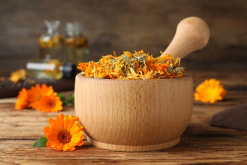 Mortar of dry calendula and fresh flowers on wooden table - obrazy, fototapety, plakaty