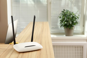 Modern wi-fi router on wooden counter indoors
