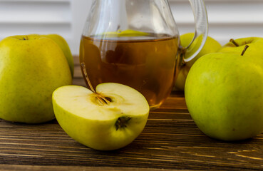 Green apples and jug with apple juice on wooden background