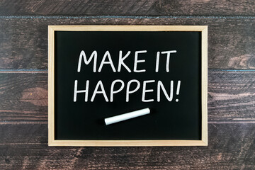 Make It Happen words on a blackboard with wooden background.