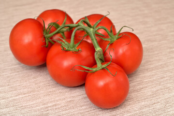 Branch with fresh ripe tomatoes on the rustic wooden table. Selective focus.
