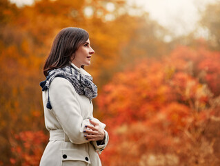 Young smiling woman walking in park on sunny autumn day