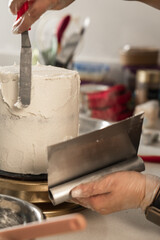 Close-up of young woman's hands decorating cake with buttercream mixture