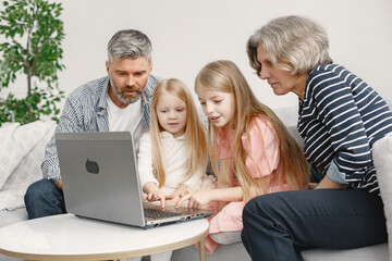 Fototapeta na wymiar Grandarents with granddaughters using laptop in the living room