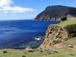 Obraz premium rugged coastline next to the fossilized cliffs at former penal colony of maria island, off the coast of triabunna, in eastern tasmania, australia, with bishop and clerk peaks in the background 