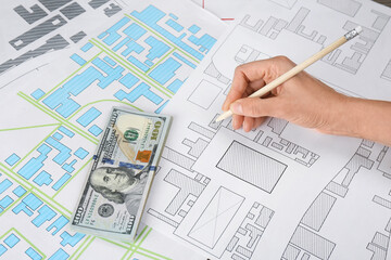 Cartographer with money drawing cadastral map, closeup
