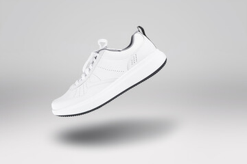 White new sneaker floating on gray background. Sport shoe close up. Street fashion style
