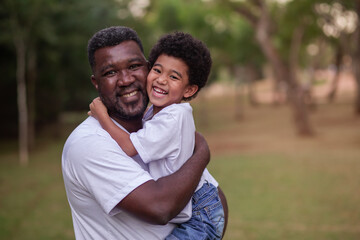 Father and afro son holding each other in the park. Father's Day.
