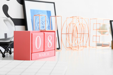 Cube calendar with date MARCH 8 on table in room, closeup