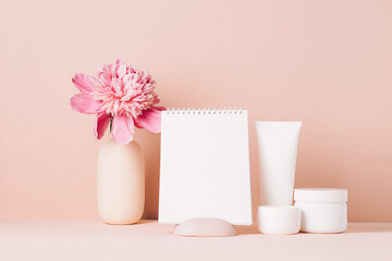 Womens accessories cream oil various cosmetics clean blank notebook on a table with flowers. Beauty concept