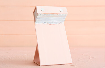 Tear-off calendar on color background, closeup
