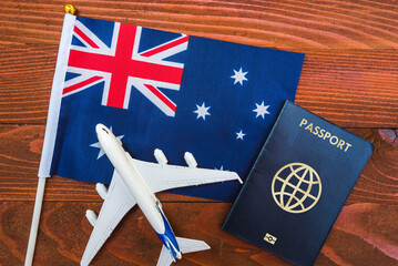 Flag of Australia with passport and toy airplane on wooden background. Flight travel concept 