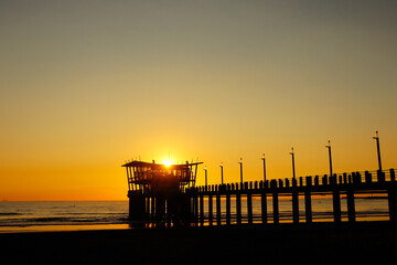 Sunrise behind pier on the beach