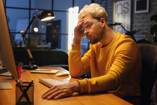 Male programmer working with computer late in evening