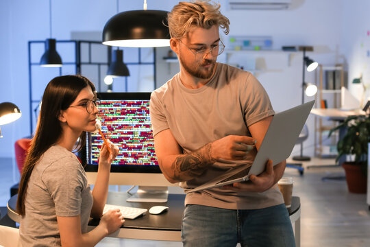 Young programmers working with laptop in office at night