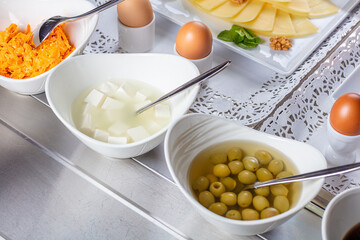 Cheese, carrots and olives in separate white bowls.