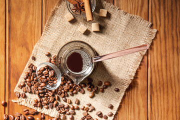 Pot with hot turkish coffee and beans on wooden background