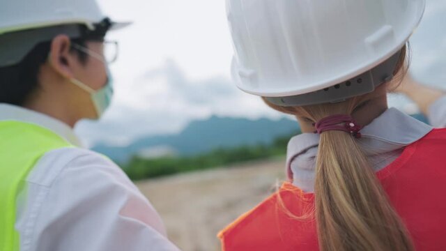 Rear view of professional builder team looking out forward analyzing on possibility of building high rise  structure on empty rough landscape, outdoor property inspection, natural mountain range view