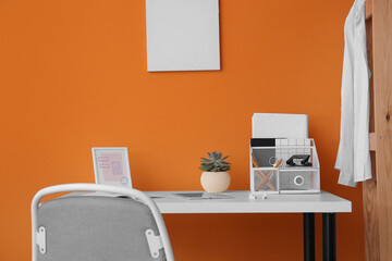 Modern workplace with tablet computer near color wall