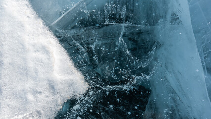 Transparent turquoise ice. In detail. Close-up. Full frame. There is some snow on the surface. Deep...