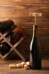 Bottle of exquisite wine and corkscrew on wooden table