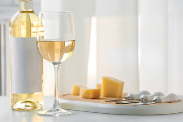 Bottle of exquisite wine, board with cheese and glass on light table