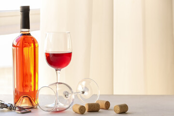 Bottle of exquisite wine, glass and corkscrew on light table in room
