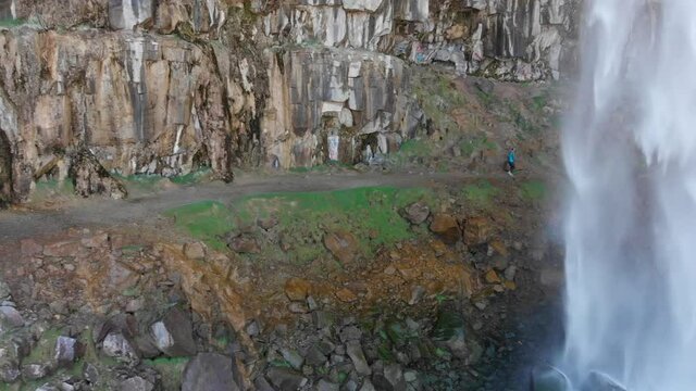 Perrine Coulee Falls in Twin Falls Idaho.  Drone footage with female walking behind waterfall.
