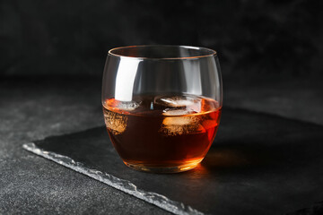 Glass of cold whiskey on dark background