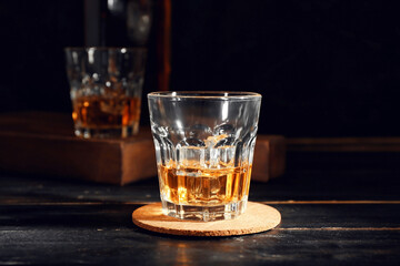 Glass of cold whiskey on dark wooden background