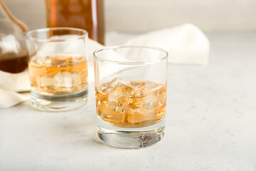 Glasses of cold whiskey on light background