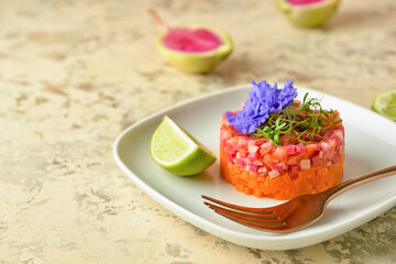 Plate with tasty tartare salad, lime and flower on color background, closeup