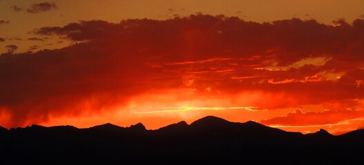 fiery sunset over the front range of the rocky mountains as seen from broomfield, colorado