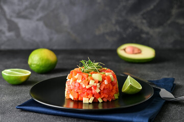 Plate with tasty tartare salad and lime on dark background, closeup