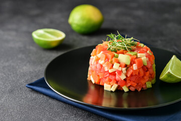 Plate with tasty tartare salad and lime on dark background, closeup