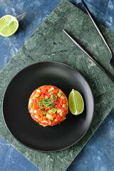 Plate with tasty tartare salad and lime on color background